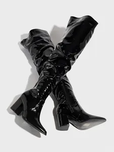 Detailed view of shiny black over-the-knee boots with pointed toe and side zipper.