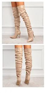 Détail de bottes cuissardes en cuir verni beige avec design plissé et talon aiguille.