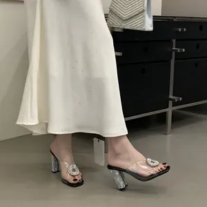Close-up showing elegant clear PVC rhinestone sandals with chunky glitter heels.