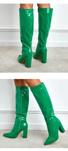 Detail of green crocodile texture knee-high boots with pointed toe and chunky heel.