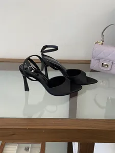 Elegantes sandalias negras de tacón alto estilo francés con correas al tobillo en estante.