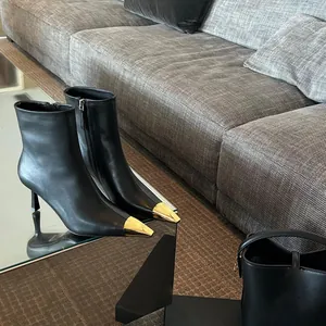 Close-up of black leather ankle boots with gold metal toe caps and stiletto heels
