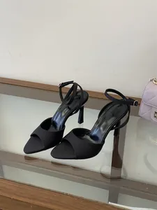 Primer plano de elegantes tacones altos de satén negro con tiras al tobillo