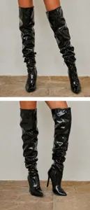 Detalle de botas mosqueteras de charol negro con diseño de textura fruncida y tacón de aguja.