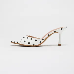 Elegant white pointed-toe high heel mule sandals with classic black polka dot pattern
