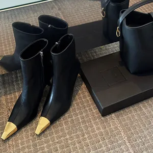 Elegant black ankle boots with pointed gold metal toe caps and thin high heels for women.
