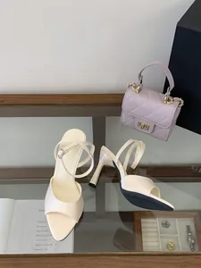 Elegantes sandalias blancas de tacón alto con punta cuadrada y correa al tobillo.