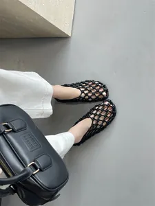 Detailed view of black hollow woven flat sandals featuring a breathable mesh design