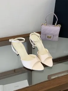 Detalle de elegantes sandalias crema de punta abierta con tira fina en el tobillo y tacón de aguja