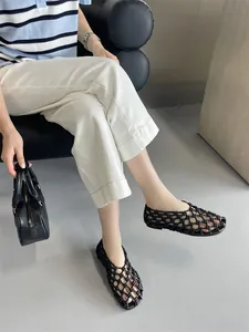 Elegant French style hollow woven breathable black flat sandals shown in a lifestyle setting