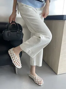 Detailed view of white hollow woven flat sandals with French chic style on model