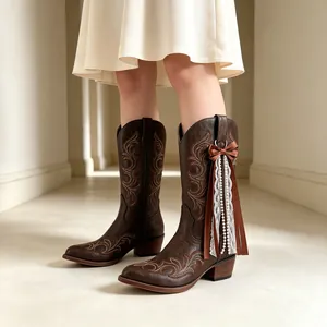 Close-up of brown cowboy boot featuring a decorative ribbon bow with pearls and lace.