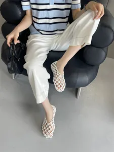 Chic white woven hollow-out flat sandals displayed in a stylish lifestyle setting