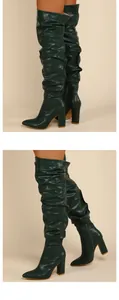 Detailed close-up view of dark green pleated over-the-knee boots with chunky high heels