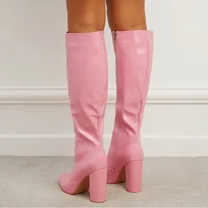 Pink crocodile-patterned knee-high boots with chunky heels and pointed toe