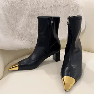 Detail view of black leather ankle boots featuring elegant metallic gold square toe caps