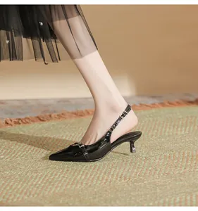 Side view of elegant black pointed-toe kitten heel slingbacks on a model's foot