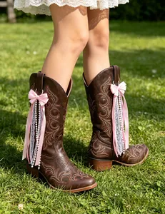 Detail of pink ribbon bow and pearl tassel charms on brown western cowboy boots