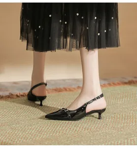 Side view of black pointed-toe slingback kitten heels worn with a mesh skirt.