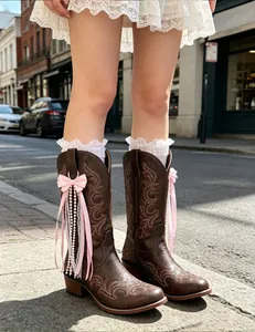 Detail view of a pink ribbon bow charm with pearls on vintage brown western cowboy boots