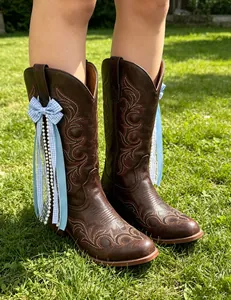 Blue gingham and lace ribbon bow charm for Western cowboy boots on a grass field