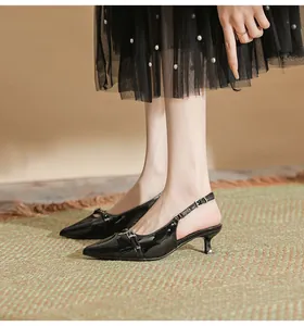 Detail shot of black patent leather kitten heel slingback shoes on model