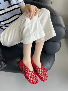Detailed close-up of vibrant red hollow woven flat sandals on feet, showcasing breathable mesh