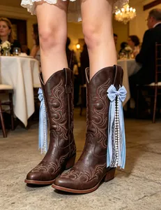 Detailed macro view of blue gingham ribbon and pearl charms on brown western boots