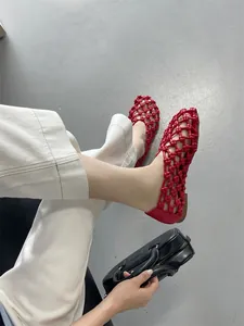 Close-up of red hollow woven flat sandals worn on feet showing the breathable French style design