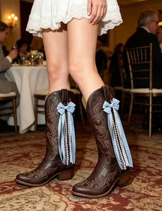 Detail view of blue gingham ribbon bow accessory attached to brown leather cowboy boots.