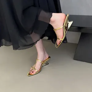 Detailansicht der stilvollen goldenen Sandalen mit architektonischem Keilabsatz.