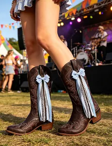 Detail view of light blue gingham bows and lace ribbons on brown Western boots.