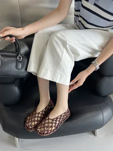 Detailed view of brown hollow woven flat sandals for women featuring a breathable design