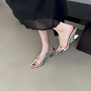 Elegante silberne Pantoletten mit Keilabsatz, getragen von einem Model in Schwarz.