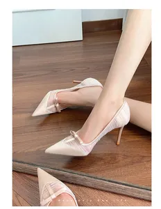 Close-up view of elegant nude pink pointed-toe pumps featuring mesh sides and a bow.