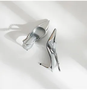 Detailed view of silver metallic stiletto slingback heels featuring a rhinestone strap