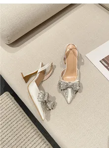 Detailansicht eleganter spitzer Slingback-Pumps mit funkelnder Strass-Schleife und Pfennigabsatz