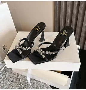 Close-up view of elegant black square-toe high heels featuring sparkling rhinestone straps
