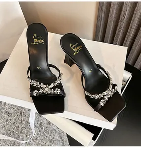 Detailed view of elegant black square-toe sandals with sparkling rhinestone floral motifs