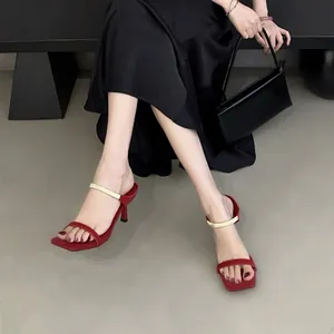 Sandales rouges chic à bout carré avec une barre métallique dorée et un talon aiguille.
