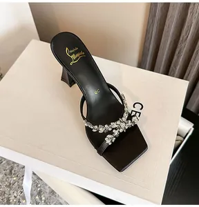 Elegant black square-toe high-heeled sandals with sparkling rhinestone bow detail.