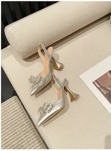 Detailansicht eleganter silberner Pumps mit Kristallschleife und ausgestelltem Absatz