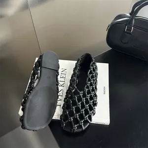 Detailed close-up of French style black woven hollow-out flat sandals on a book.