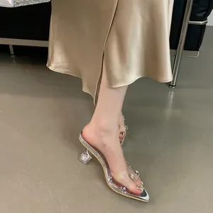 Close-up of silver pointed-toe mules with rhinestones and transparent crystal heels.