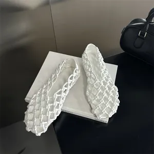 Detail view of elegant white hollow woven flat sandals for women on minimalist background