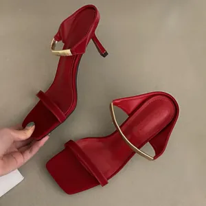 Vue détaillée de mules rouges à bout carré et talon aiguille avec une bride dorée