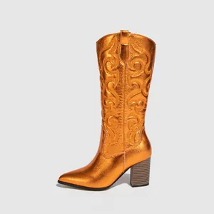 Side detail of metallic orange cowboy boots featuring intricate embroidery and chunky heels
