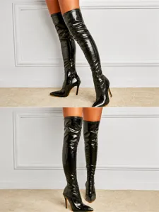 Detalle de botas negras por encima de la rodilla con relieve de cocodrilo y tacón