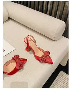 Detailansicht roter spitze Slingback-Pumps mit funkelnder Strass-Schleife am Vorderfuß