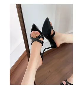 Detailed view of black patent leather stiletto mules with crisscross straps design